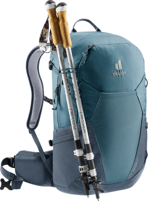 Deuter Futura 27 ryggsäck i blått, visad från sidan med två vandringsstavar fästa på utsidan – perfekt för dagsturer och fjällvandring med praktiska fästöglor och vadderat höftbälte för komfort.