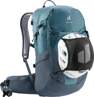 Deuter Futura 27 vandringsryggsäck i Atlantic / Ink-blå med ventilerande Aircomfort-bärrsystem, höftbälte och justerbara axelremmar – visad i profil med det medföljande svarta hjälmnätet fastspänt framtill över en vit cykelhjälm.