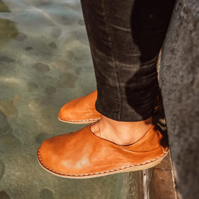 Fötter i skor från VIBAe i cognacfärgat läder – närbild på skor vid vattenkant