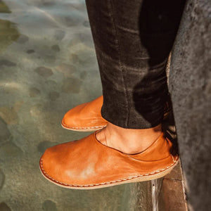 Fötter i skor från VIBAe i cognacfärgat läder – närbild på skor vid vattenkant