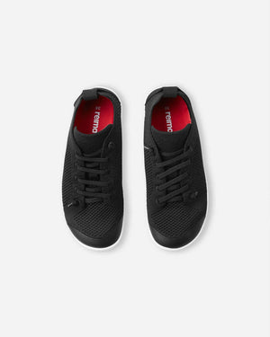 Reima Astelu barfotasko Black – svart minimalistisk barnsko med vit sula, stickad ovandel och bred tåbox för naturlig rörelsefrihet.