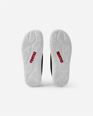 Undersidan av Reima Astelu barfotasko Black – svart minimalistisk barnsko med vit sula, stickad ovandel och bred tåbox för naturlig rörelsefrihet.