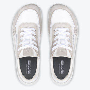Produktbild av barfotaskon Skinners Allrounder White fotograferad uppifrån. Bilden visar ett par skor med bred tåbox, vit mesh och ljusgrå mockadetaljer. Skorna är parallellt placerade med tydlig sikt på snörning och innersula där Skinners-loggan och texten “Made in Portugal” är tryckta. Den symmetriska layouten framhäver skons minimalistiska och fotformade design.